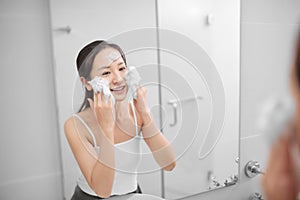 Beautiful young woman washing her face foam in a bathroom