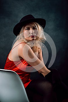 beautiful young woman wear elegant red dress and black hat isolated on dark background