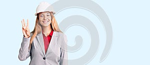 Beautiful young woman wearing architect hardhat showing and pointing up with fingers number three while smiling confident and