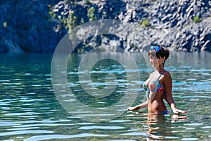 Beautiful young woman wearing a bikini standing in a mountain la