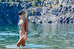 Beautiful young woman wearing a bikini standing in a mountain ri