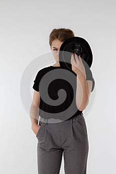 Beautiful young woman wearing black hat on light background. No face