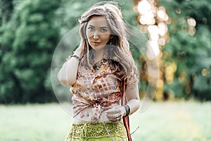 Beautiful young woman wearing bohostyle clothes posing in the rays of the evening sun, sunset. Boho style fashion