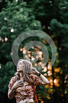 Beautiful young woman wearing bohostyle clothes posing in the rays of the evening sun, sunset. Boho style fashion photo