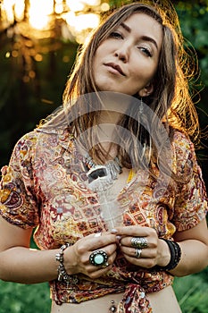 Beautiful young woman wearing bohostyle clothes posing in the rays of the evening sun, sunset. Boho style fashion photo