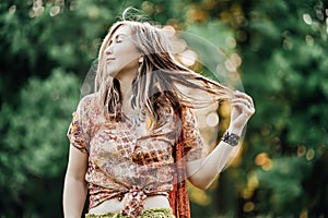 Beautiful young woman wearing bohostyle clothes posing in the rays of the evening sun, sunset. Boho style fashion photo