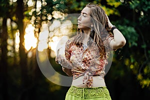 Portrait of Beautiful young woman wearing bohostyle clothes posing in the rays of the evening sun, sunset. Boho style photo