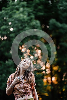 Beautiful young woman wearing bohostyle clothes posing in the rays of the evening sun, sunset. Boho style fashion photo