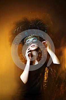 Beautiful young woman wearing carnival mask with feathers