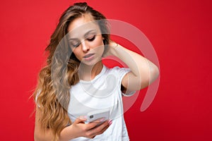 Beautiful young woman wearing casual clothes standing isolated over background surfing on the internet via phone looking