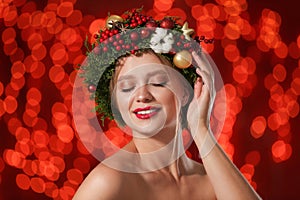 Beautiful young woman wearing Christmas wreath on blurred background