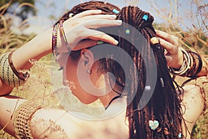 Beautiful young woman wearing dreadlocks hairstyle gathered in a ponytail and decorated assorted beads