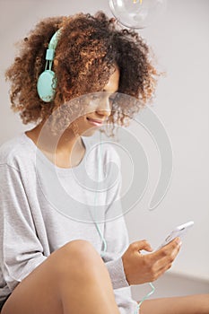 Beautiful young woman wearing headphones and listening musing on mobile phone.