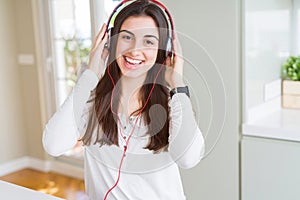 Beautiful young woman wearing headphones listening to music, enjoying and dancing happy