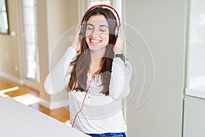 Beautiful young woman wearing headphones listening to music, enjoying and dancing happy