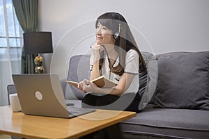 Beautiful young woman wearing headset is making video conference call via computer at home