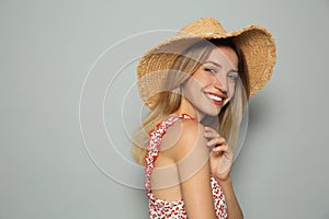 Beautiful young woman wearing straw hat on light grey background, space for text. Stylish headdress