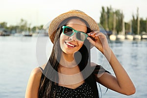 Beautiful young woman wearing stylish sunglasses near river