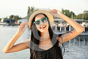 Beautiful young woman wearing stylish sunglasses near river