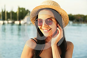 Beautiful young woman wearing stylish sunglasses near river