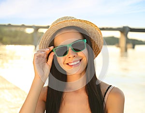 Beautiful young woman wearing stylish sunglasses near river