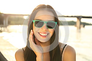 Beautiful young woman wearing stylish sunglasses near river