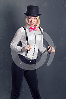 Beautiful young woman wearing tophat, bow-tie and braces against