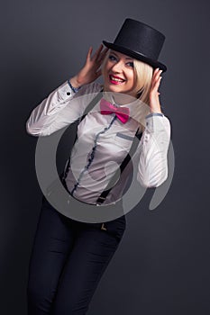 Beautiful young woman wearing tophat, bow-tie and braces against