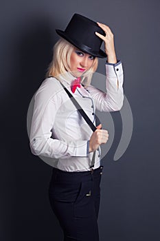 Beautiful young woman wearing tophat, bow-tie and braces against