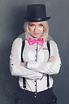 Beautiful young woman wearing tophat, bow-tie and braces against