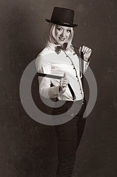 Beautiful young woman wearing tophat, bow-tie and braces against