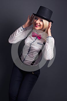 Beautiful young woman wearing tophat, bow-tie and braces against photo