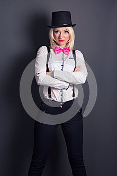 Beautiful young woman wearing tophat, bow-tie and braces against photo