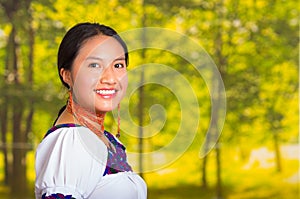 Beautiful young woman wearing traditional andean blouse with necklace, standing posing for camera, smiling happily