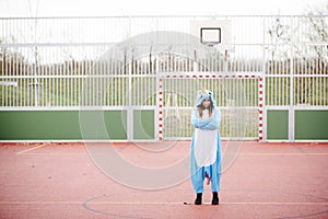 Beautiful young woman wearing turquoise unicorn onesie in urban environment