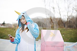 Beautiful young woman wearing turquoise unicorn onesie in urban environment