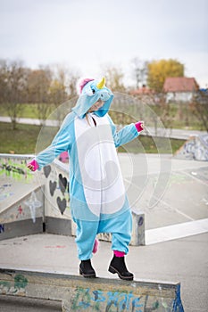 Beautiful young woman wearing turquoise unicorn onesie in urban environment