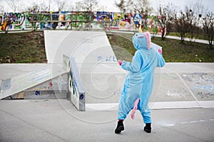 Beautiful young woman wearing turquoise unicorn onesie in urban environment