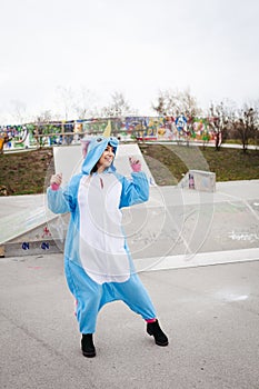 Beautiful young woman wearing turquoise unicorn onesie in urban environment