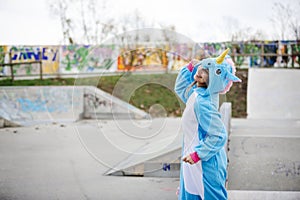 Beautiful young woman wearing turquoise unicorn onesie in urban environment