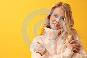 Beautiful young woman wearing warm pink sweater on yellow background. Space for text