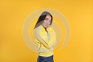 Beautiful young woman wearing warm sweater on yellow background