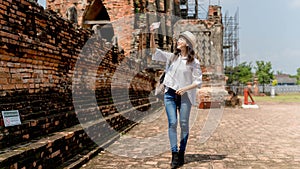 Beautiful young woman wearing white shirt and hat taking photo by mobile in temple ayutthaya thailand, Travel Holiday Relaxation