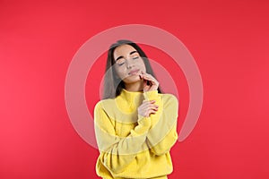 Beautiful young woman wearing yellow warm sweater on red background