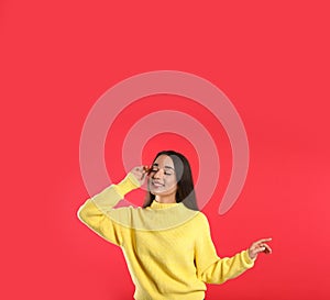 Beautiful young woman wearing yellow warm sweater on red background