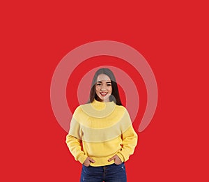 Beautiful young woman wearing yellow warm sweater on red background