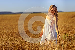 Beautiful young woman in wheat field at sunset outdoor