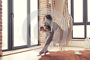 Woman wearing cashmere nightwear relaxing in cabin near fireplace