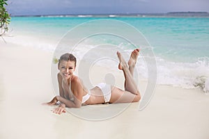 Beautiful young woman in a white bikini on a sandy tropical beach