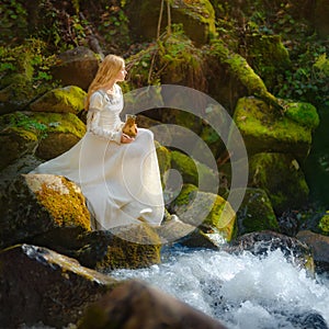 Beautiful young woman in a white dress in the middle of a forest